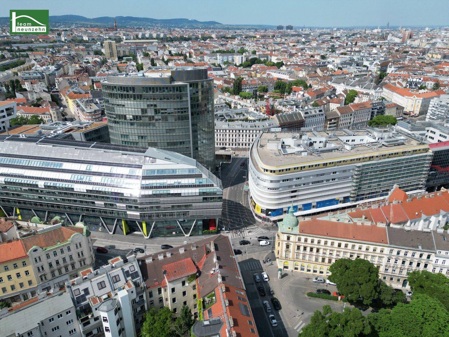Luftaufnahme eines modernen Stadtviertels mit markanten Glasfassaden und geschwungenen Gebäuden.