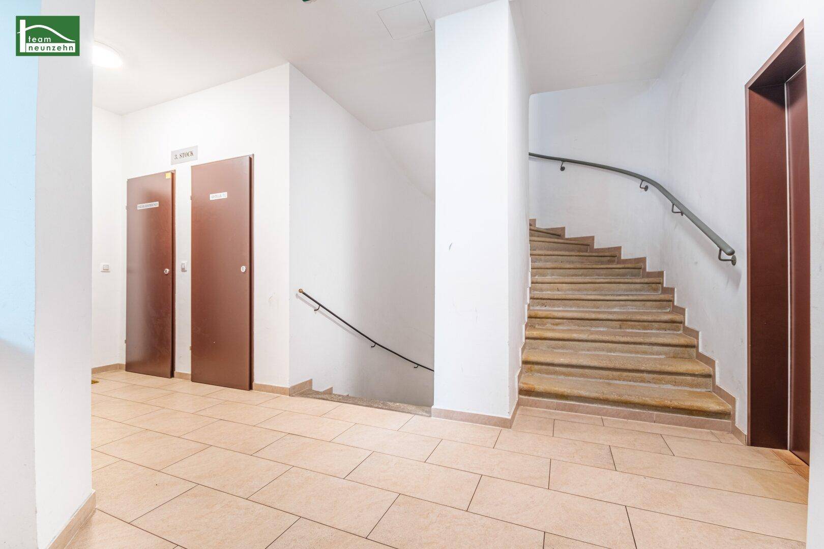 Treppenhaus mit Steinstufen und Handlauf, das zu den oberen Etagen führt.