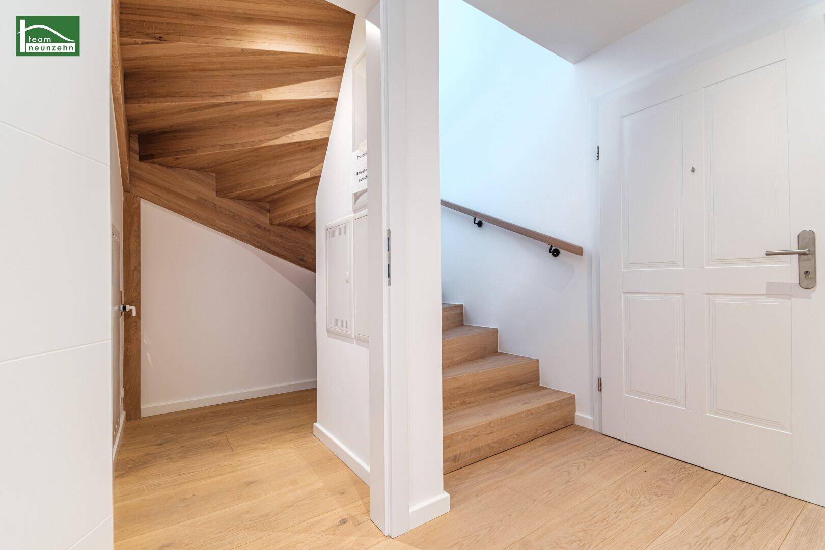 Heller Flur mit Holztreppe, Holzboden und modernem Geländer.