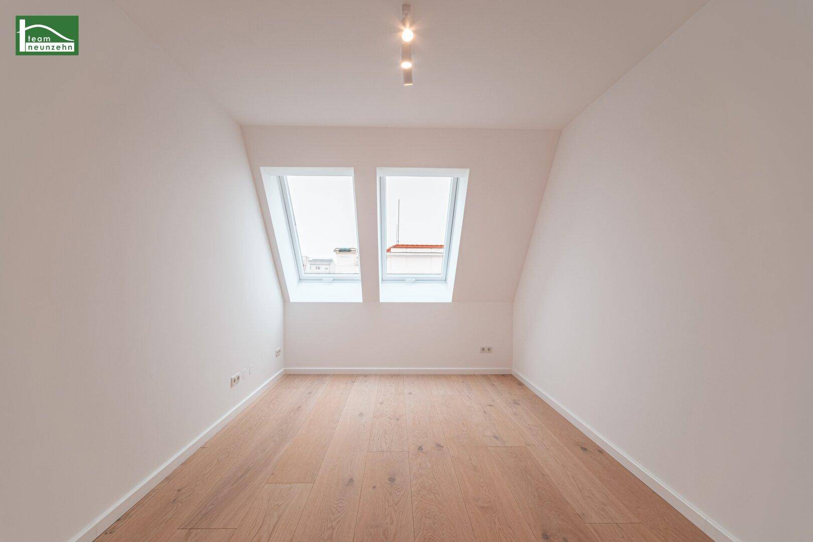 Gemütliches Schlafzimmer im Dachgeschoss mit Holzboden und zwei Dachfenstern.