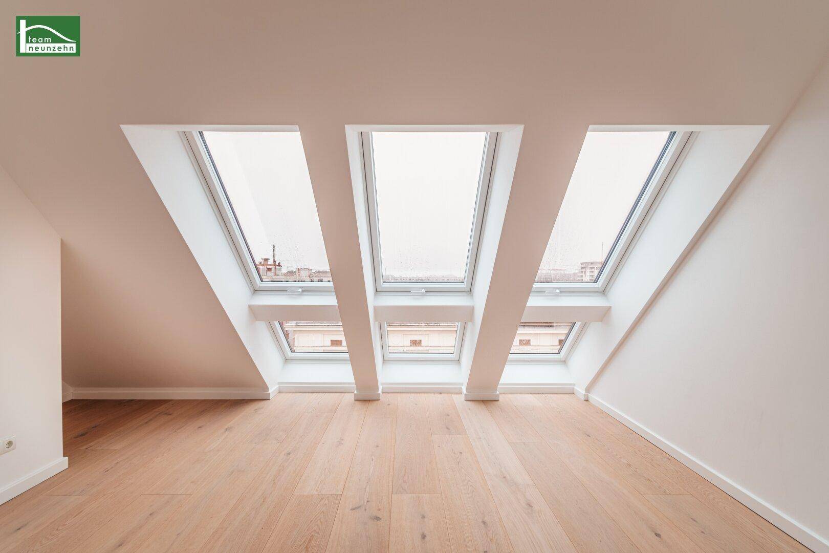 Helles Dachgeschosszimmer mit Holzboden und einer Reihe von Dachfenstern für optimale Belichtung.