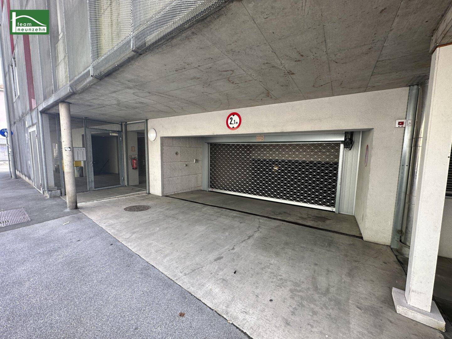 Eingang zu einer Tiefgarage mit Rolltor und Höhenbegrenzung von 2,1 Metern.
