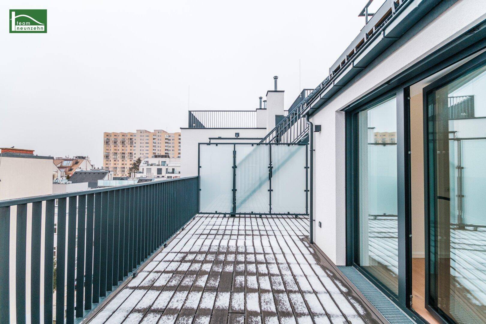 Weitläufige Dachterrasse mit Metallgeländer und Blick über die Stadt.
