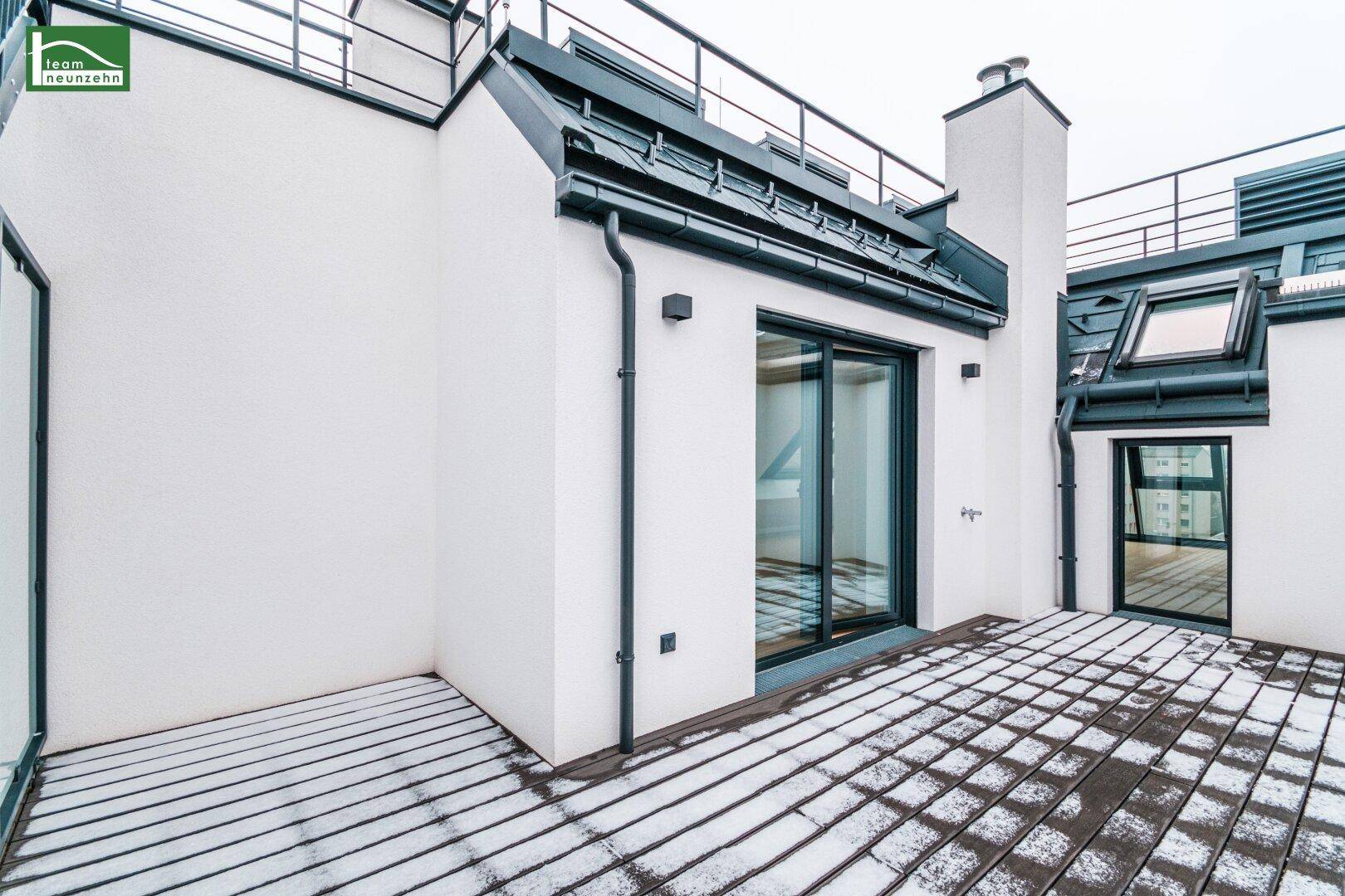 Große Dachterrasse mit Holzboden und Blick auf die umliegenden Gebäude.