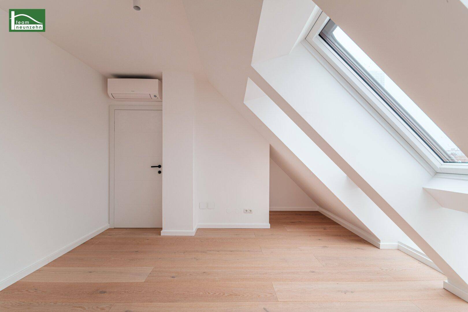 Geräumiges Dachgeschosszimmer mit Holzboden, Klimaanlage und schrägen Wänden.