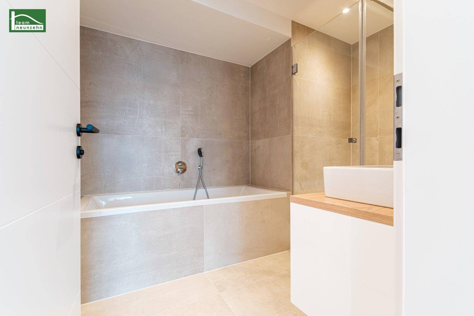 Modernes Badezimmer mit Badewanne, Waschbecken und hellen Fliesen.