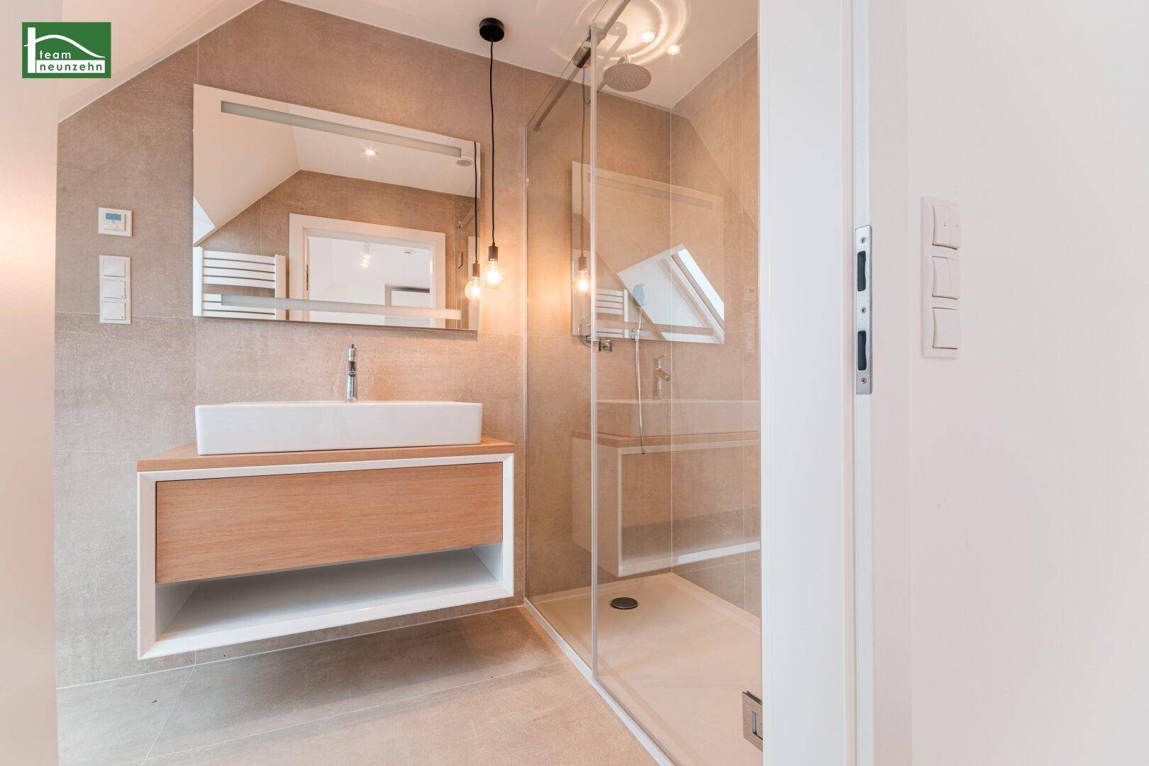 Elegantes Badezimmer mit großer Dusche, modernem Waschtisch und Dachfenster.