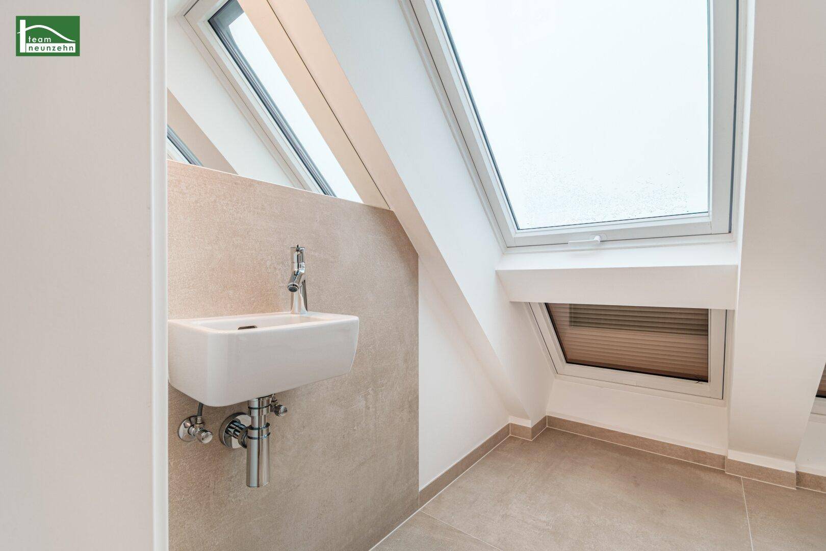 Helles WC mit Waschbecken und Dachfenster, modern gefliest.