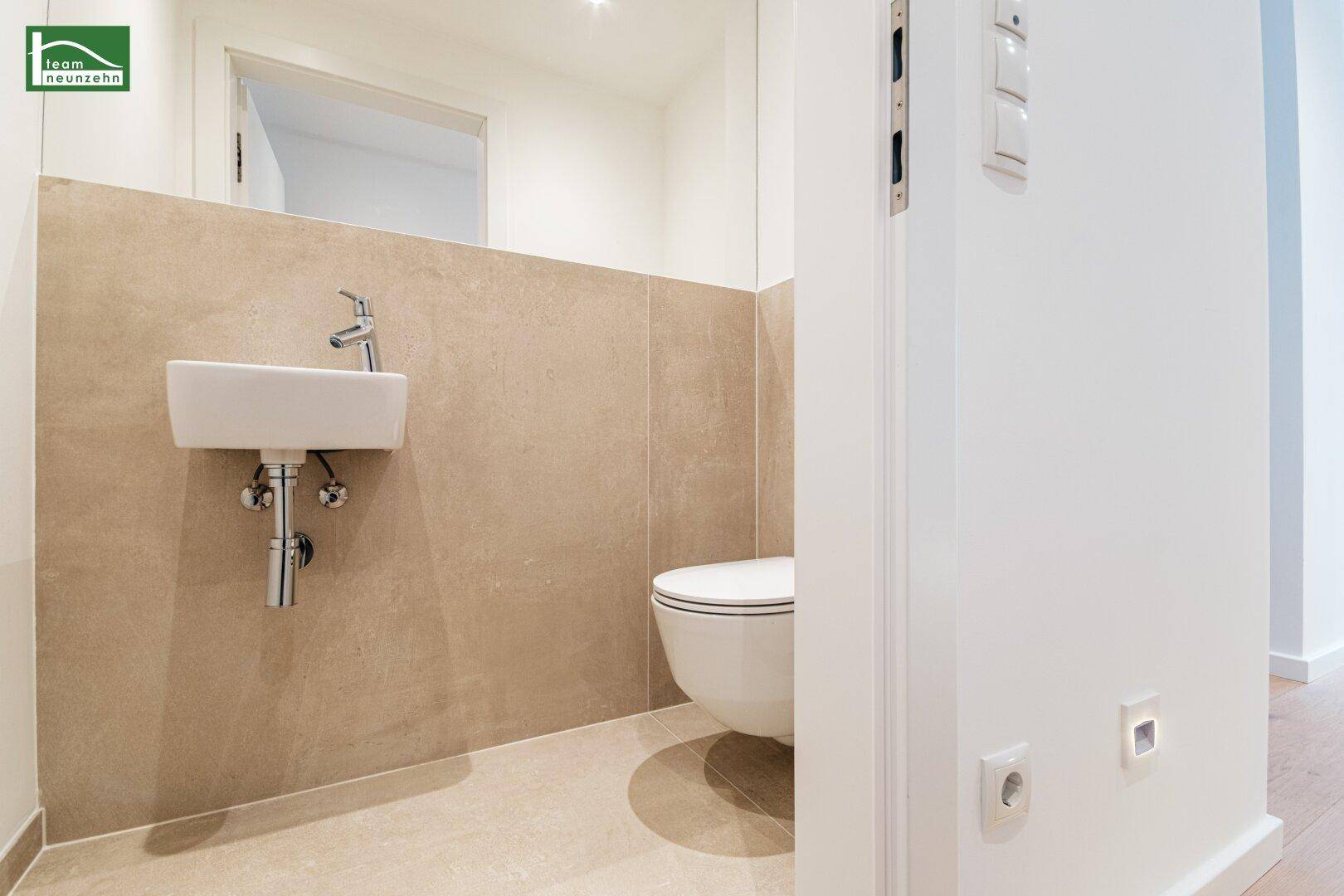 Kleines WC mit Waschbecken und wandhängender Toilette, modern gefliest.