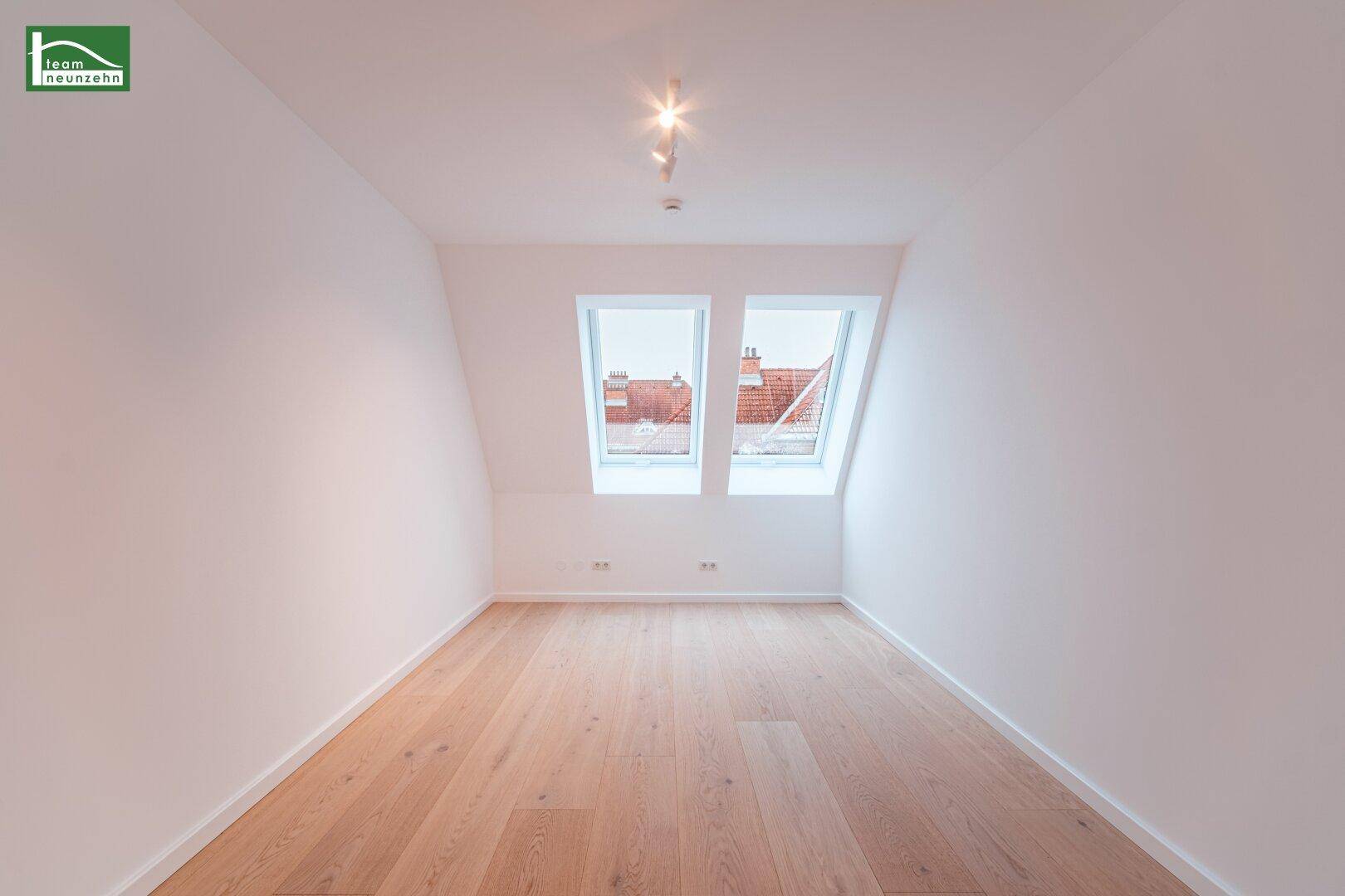 Helles Dachzimmer mit zwei Dachfenstern und neuem Holzfußboden, ideal als Schlaf- oder Arbeitszimmer.