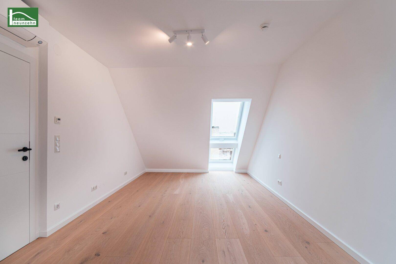 Dachzimmer mit einem Dachfenster, Klimaanlage und modernem Holzfußboden.