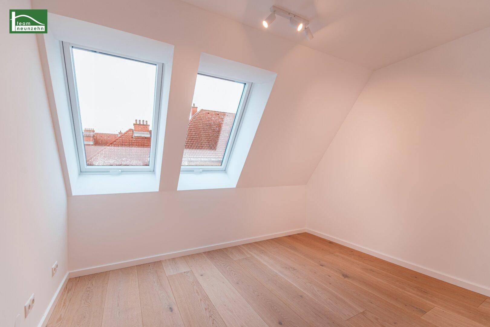 Dachzimmer mit zwei Dachfenstern und hellem Holzfußboden, bietet viel natürliches Licht.