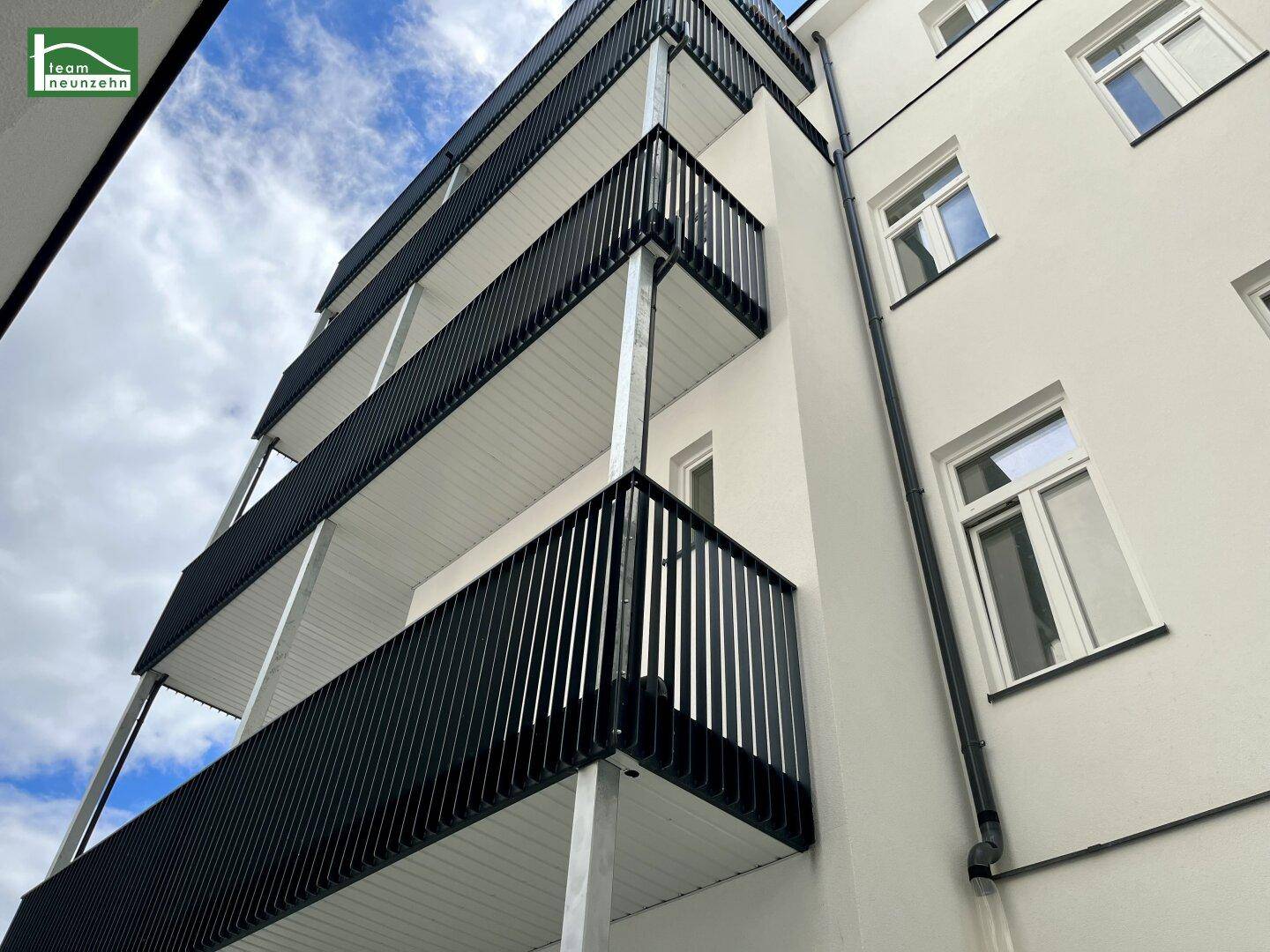Moderne Gebäudefassade mit mehreren Balkonen und klaren Linien unter blauem Himmel.