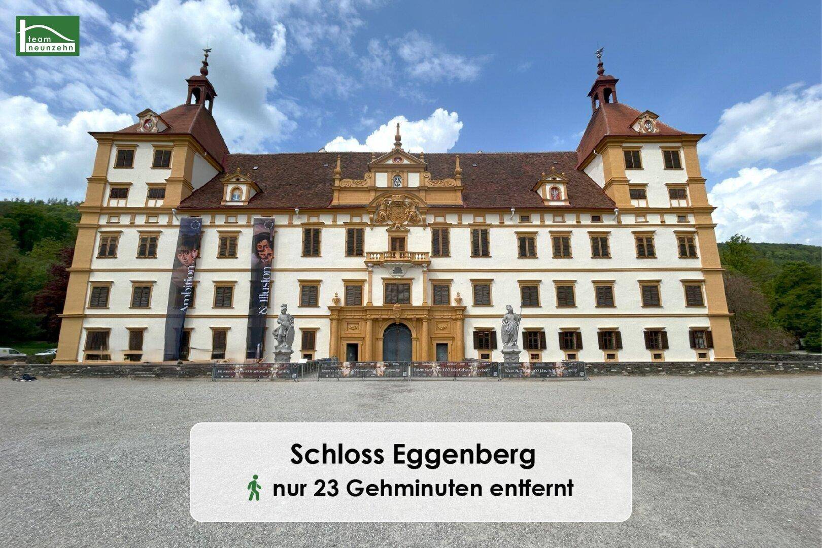 Historisches Schloss Eggenberg mit imposanter Fassade und Türmen unter blauem Himmel, umgeben von einer weiten Kiesfläche.