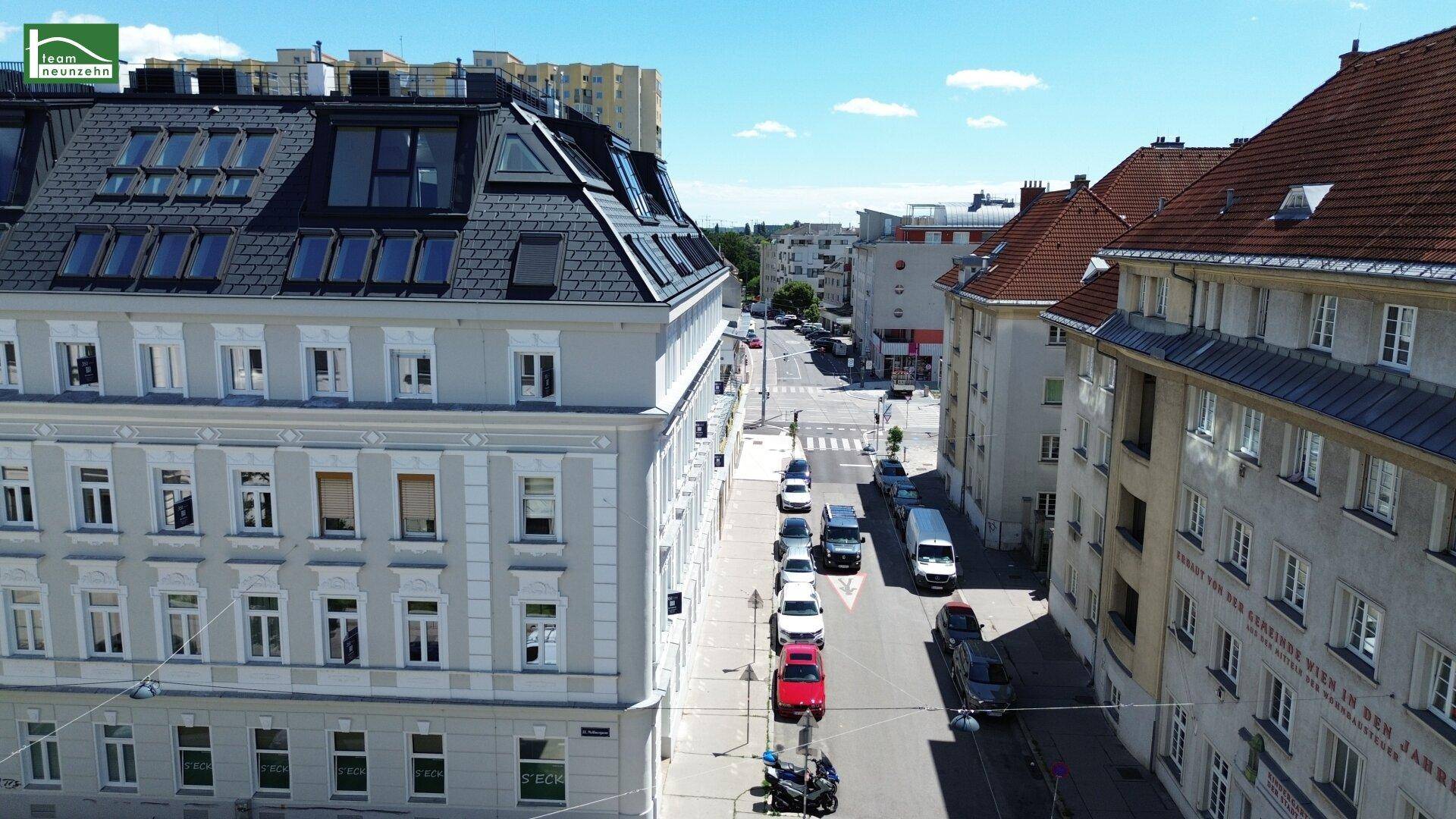 Weitläufige Straßenansicht mit Gebäuden und parkenden Autos, die die städtische Umgebung zeigen.