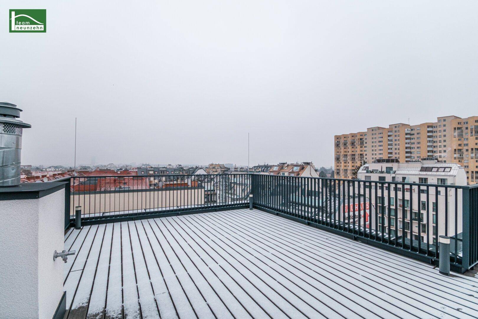 Breite Dachterrasse mit weitem Stadtblick, bedeckt mit einer Schneeschicht.