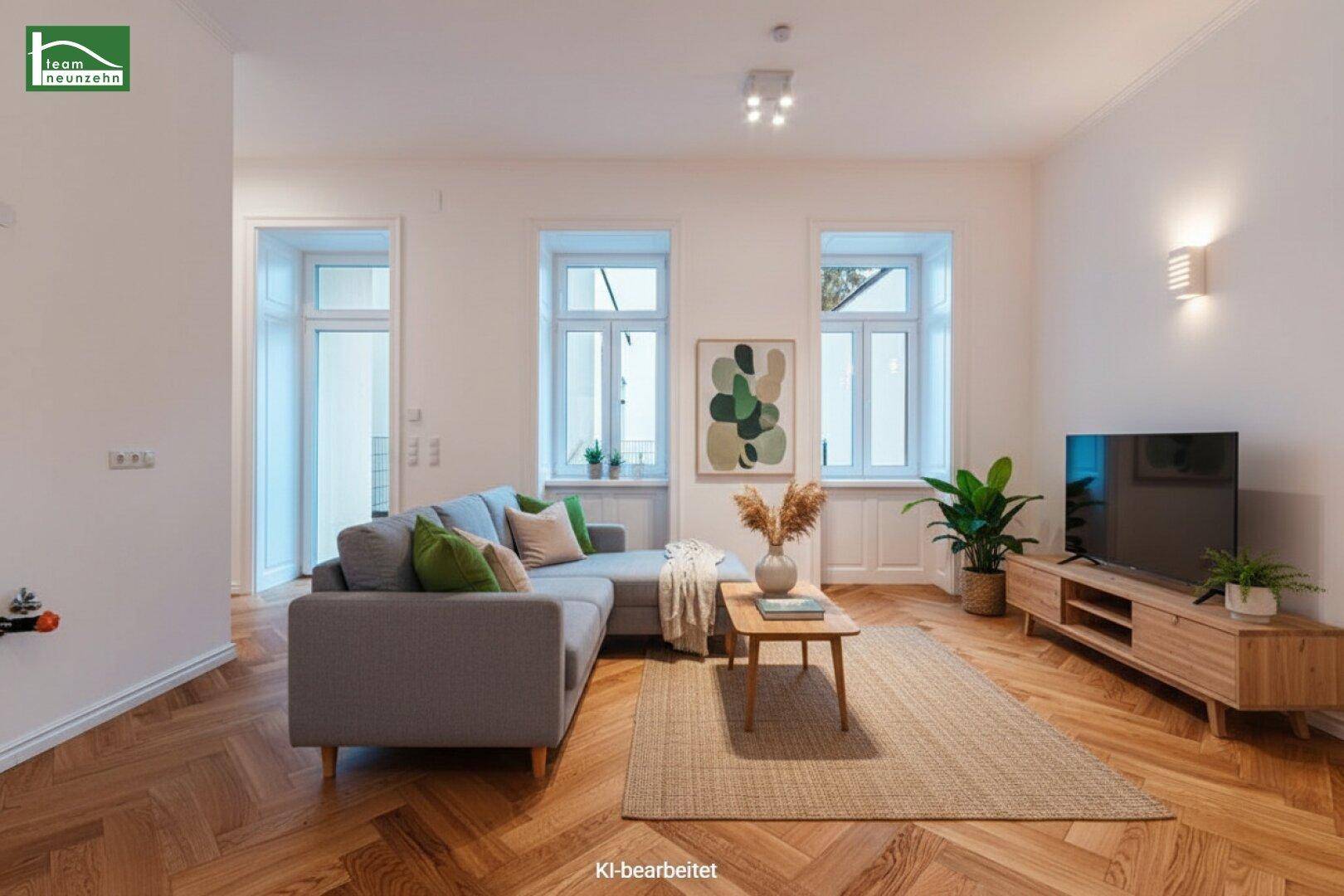 Gemütlicher Wohnbereich mit modernem Sofa, Fischgrätparkett und Blick ins Grüne.