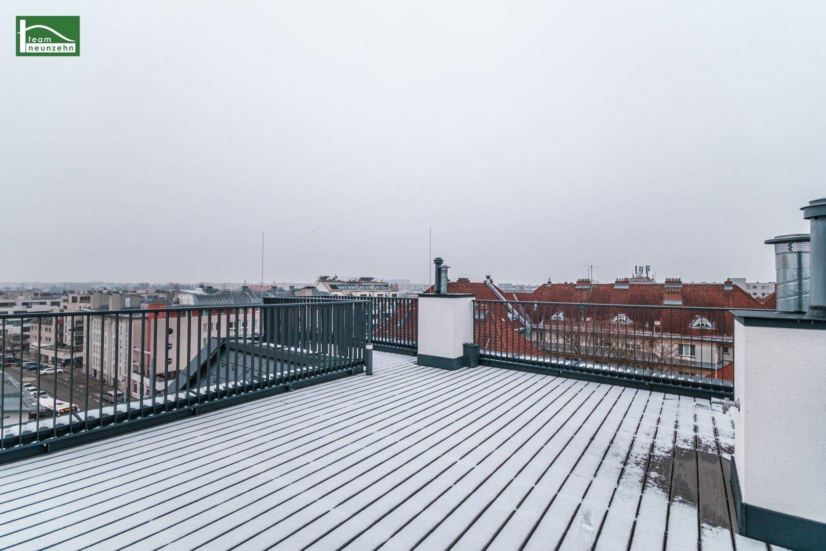 Weitläufige Dachterrasse mit Schnee bedeckt und Panoramablick über die Stadt.