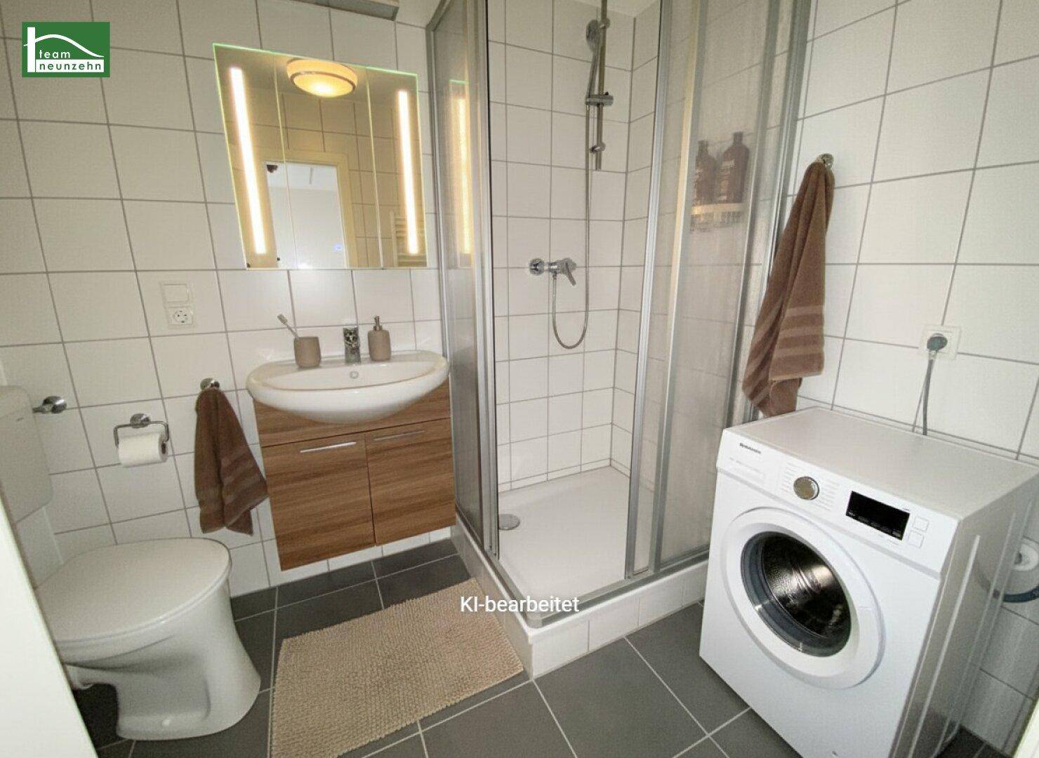 Modernes Badezimmer mit Dusche, WC, Waschbecken und Waschmaschine, hell gefliest.