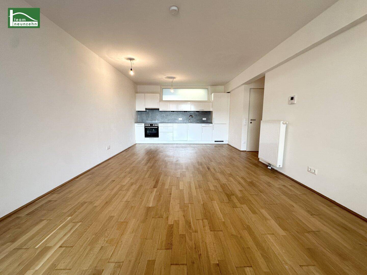 Offener Wohnbereich mit integrierter moderner Küche und Holzboden.