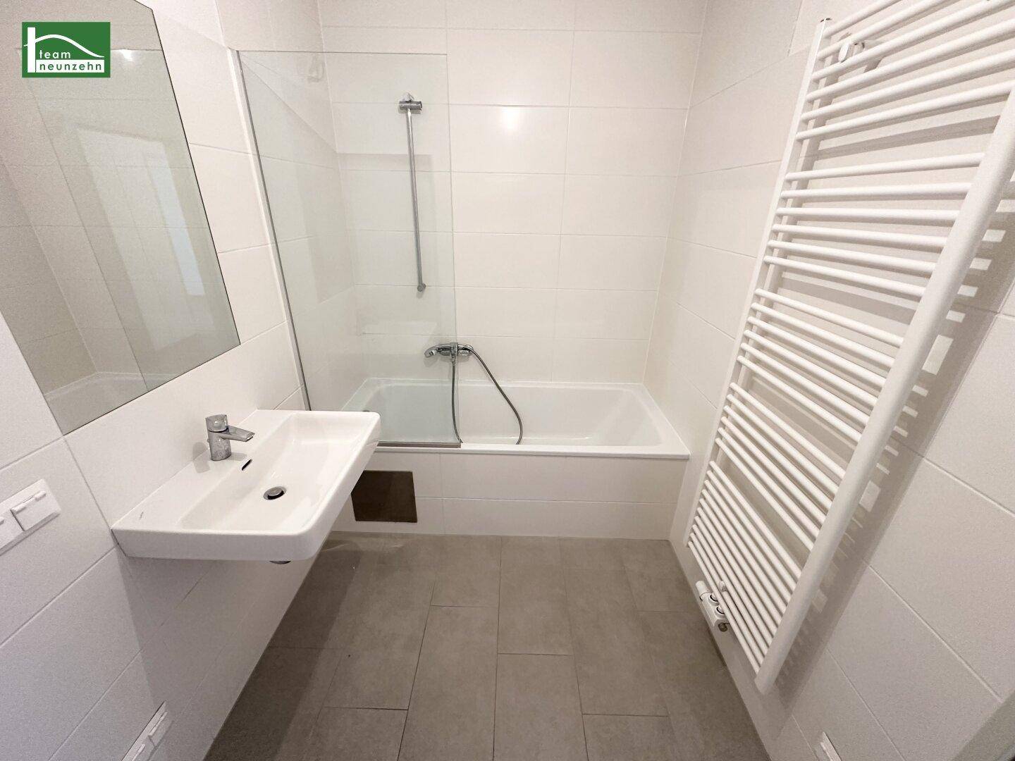 Modernes Badezimmer mit Badewanne, Duschabtrennung und beheiztem Handtuchhalter.