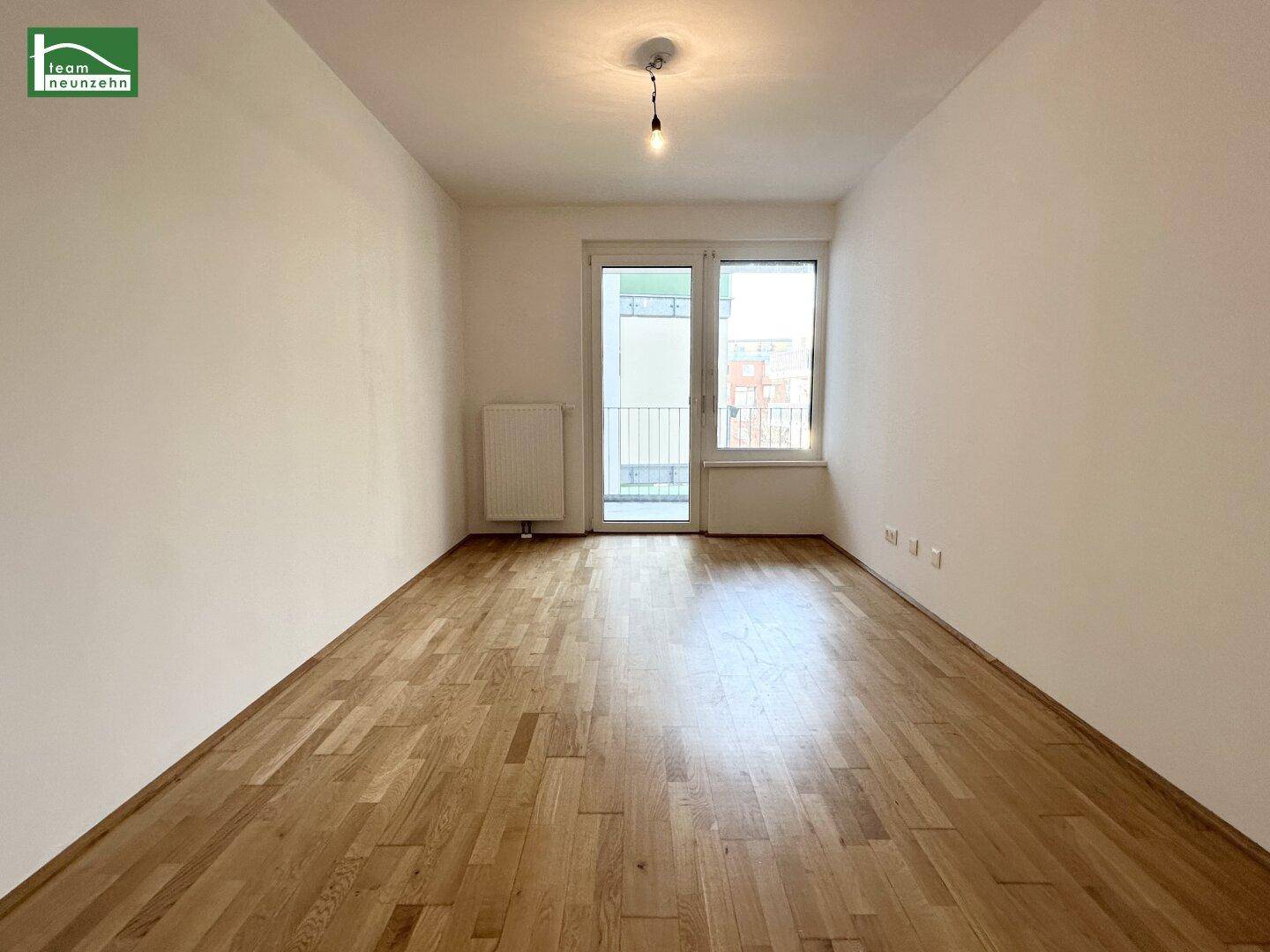 Leeres Schlafzimmer mit Holzboden und Balkonzugang, bereit zur individuellen Gestaltung.