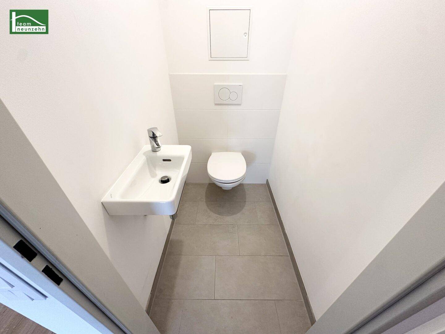 Kompaktes Gäste-WC mit modernem Waschbecken und Wand-WC.