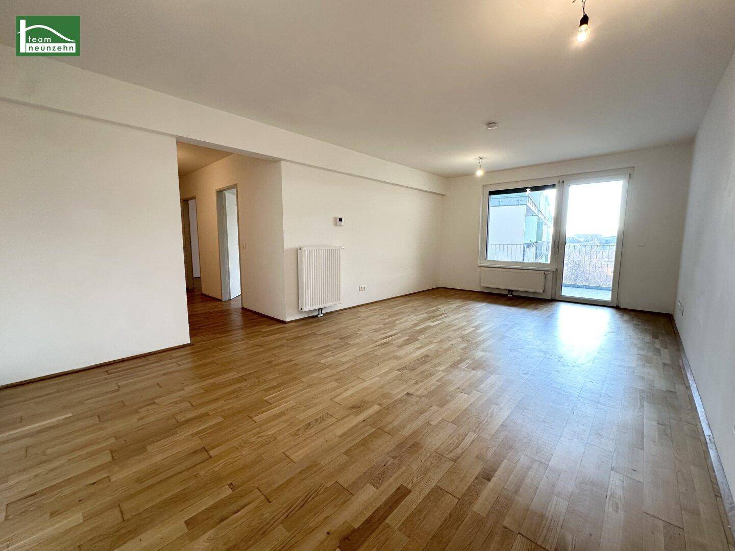 Geräumiger Wohnbereich mit Holzboden und direktem Zugang zu einem Balkon.