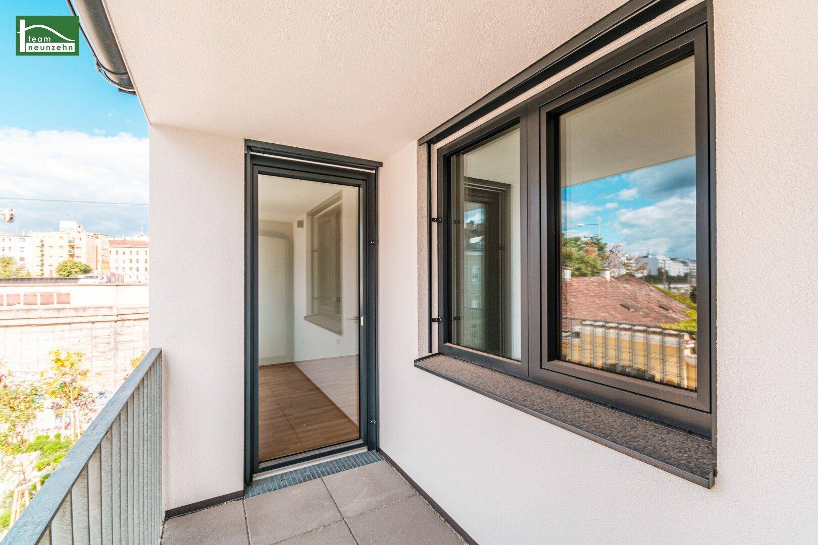 Kleiner Balkon mit Fliesenboden und Blick auf die Stadt und umliegende Gebäude.