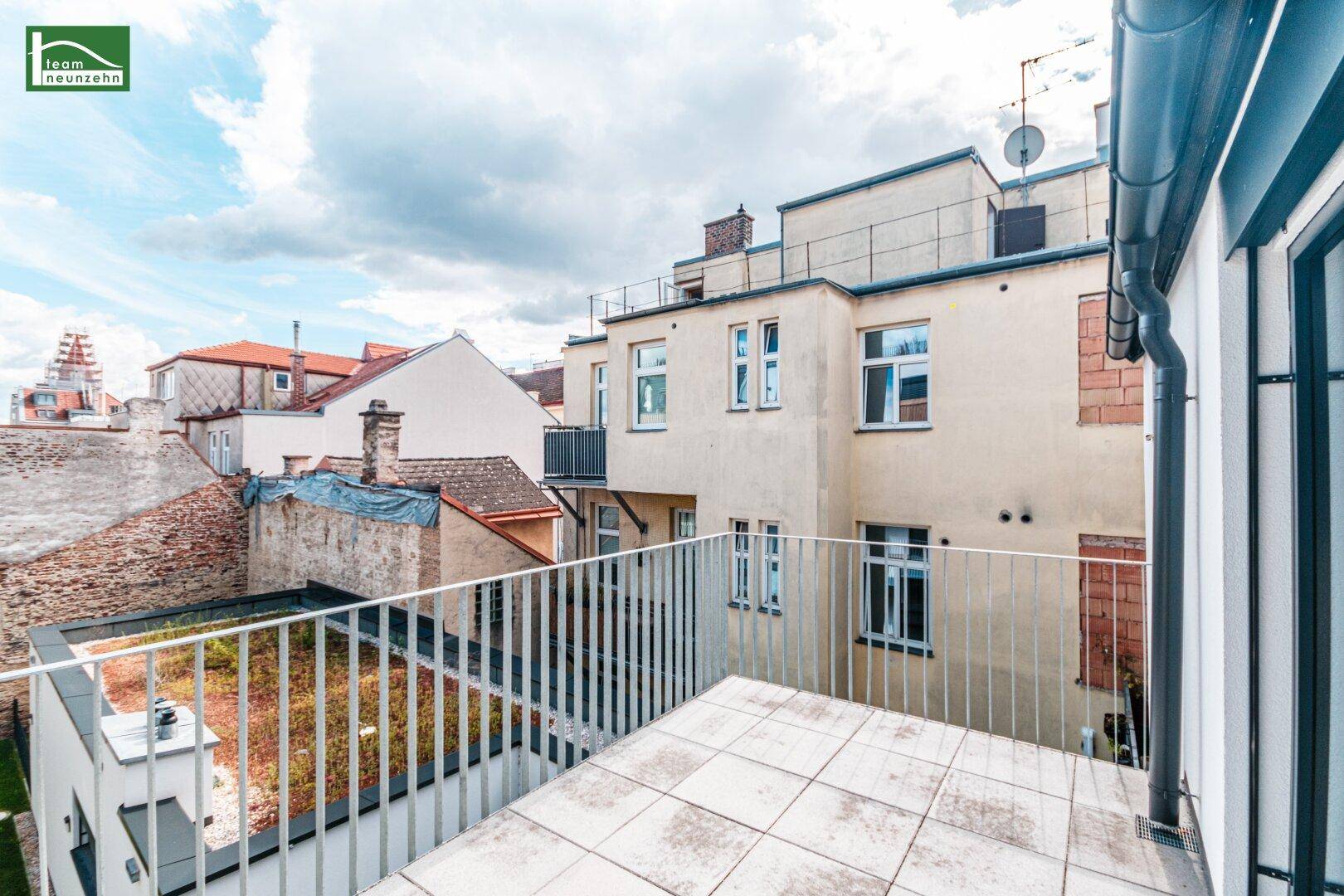 Geräumige Dachterrasse mit Fliesenboden und Blick auf die umliegenden Gebäude.