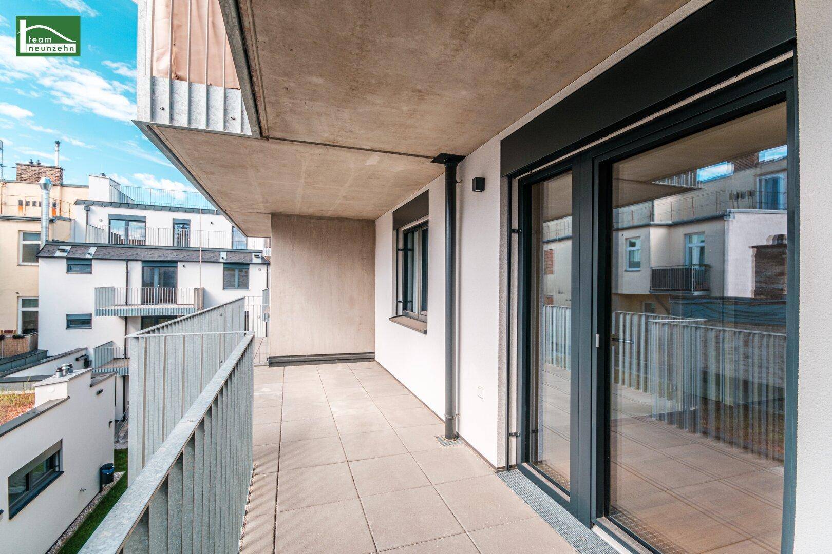 Heller Balkon mit moderner Brüstung und Schiebetüren, bietet einen Blick auf die Nachbarschaft.