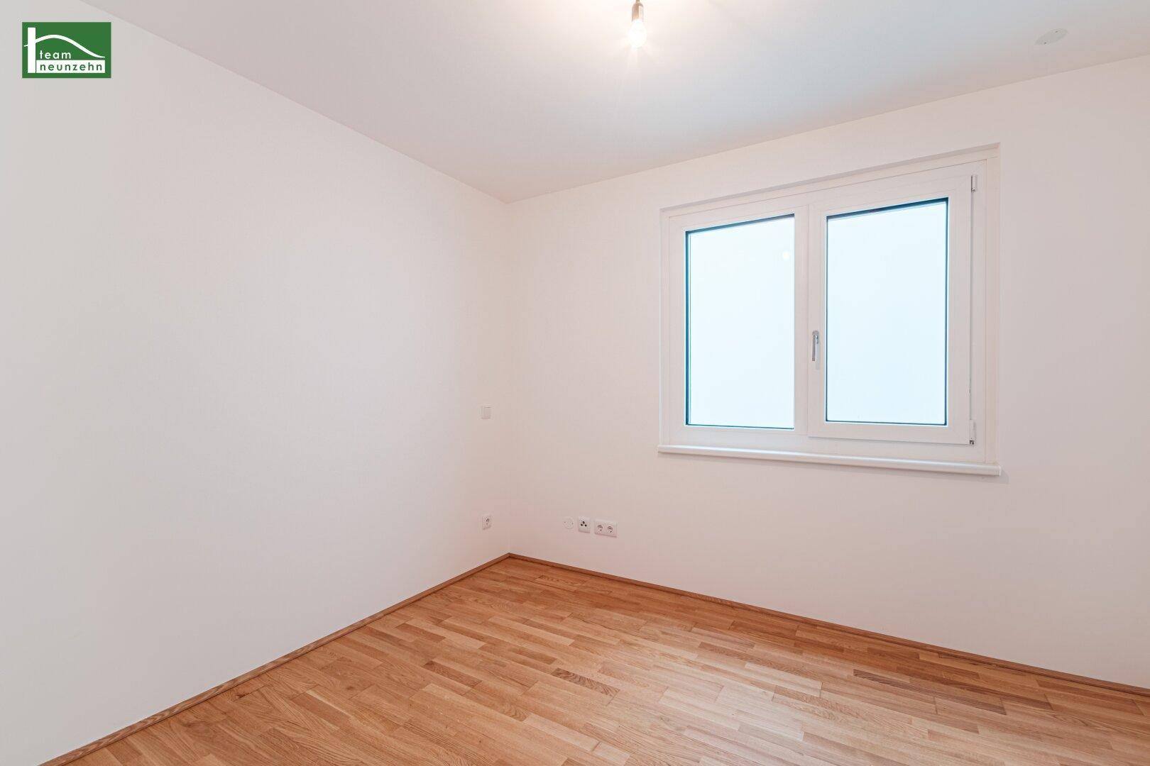 Helles Zimmer mit Parkettboden und großem Fenster, bietet viel natürliches Licht.