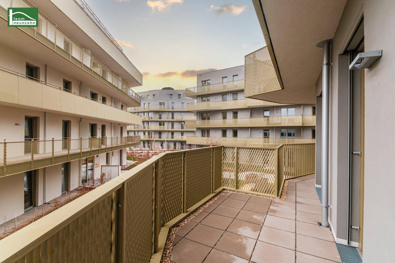 Weitläufiger Balkon mit moderner Brüstung und Blick auf die Wohnanlage.