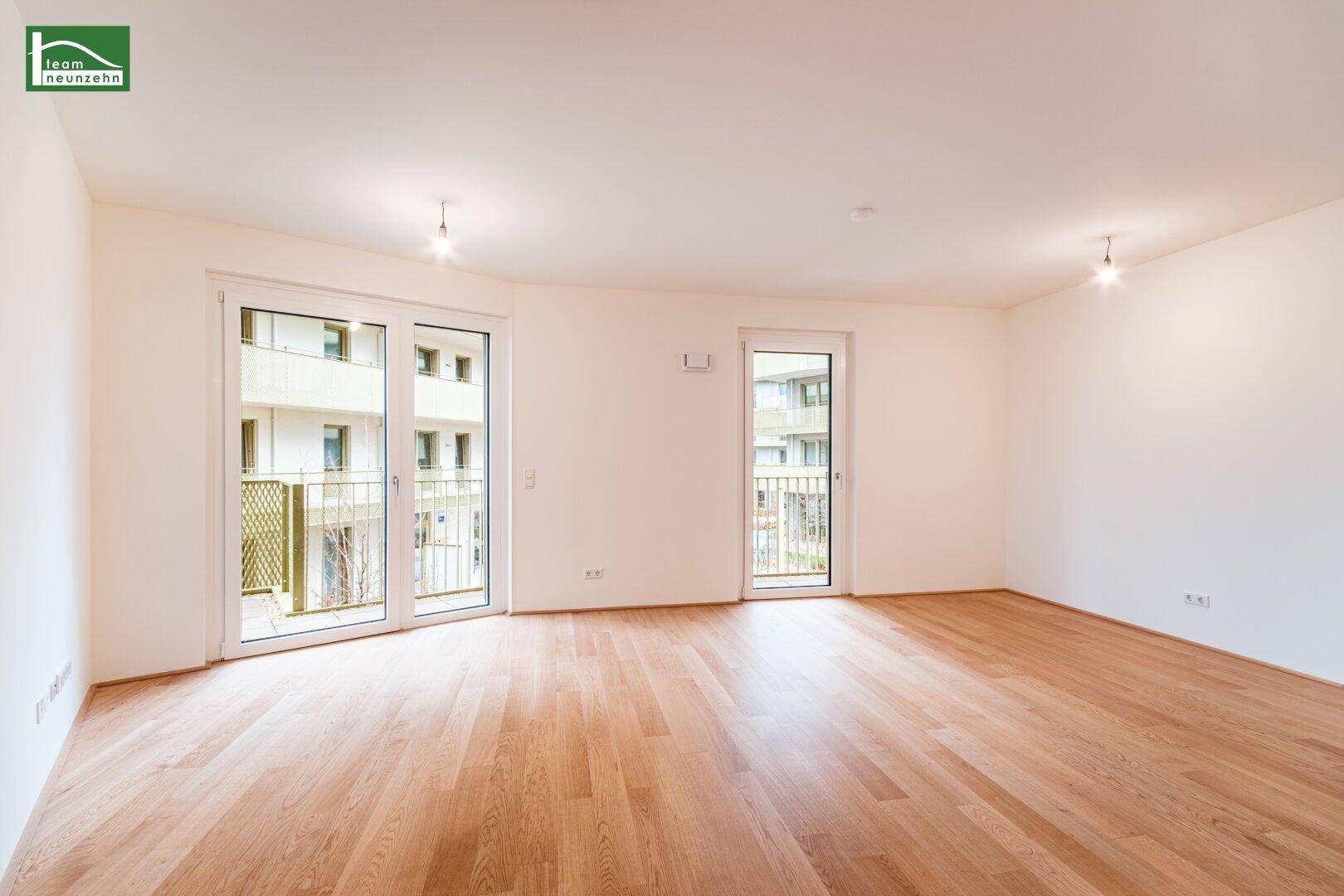 Geräumiges, helles Zimmer mit Holzboden und zwei Zugängen zu Außenbereichen.