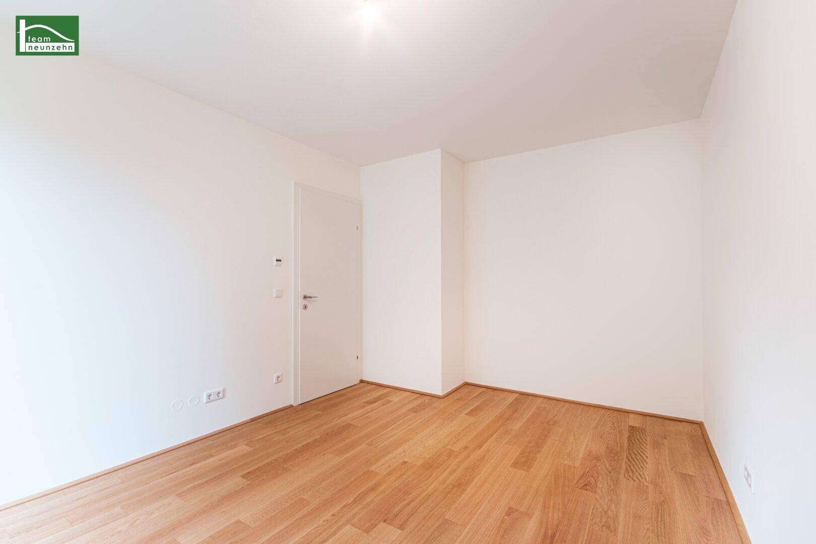 Leeres Schlafzimmer mit Holzboden und weiß gestrichenen Wänden.