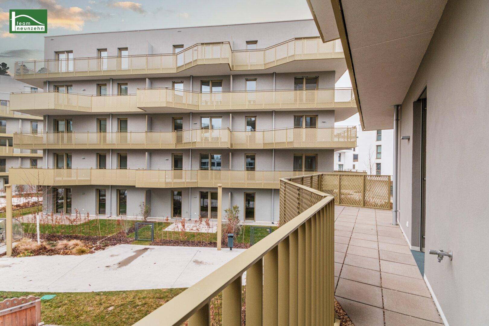 Geräumiger Balkon mit Fliesenboden und Blick auf den begrünten Innenhof, ideal zum Entspannen.