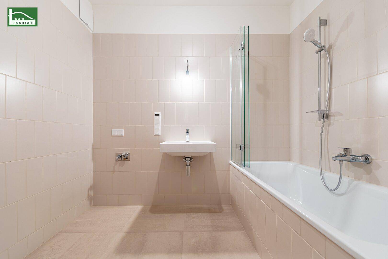 Modernes Badezimmer mit Badewanne, Dusche und hellem Fliesenboden.