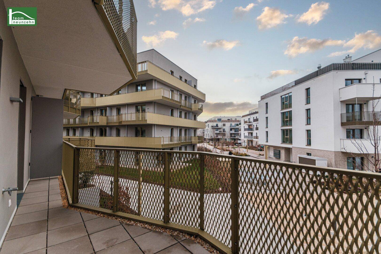 Geräumiger Balkon mit moderner Metallbrüstung und Blick auf die umliegenden Wohngebäude und den Innenhof.