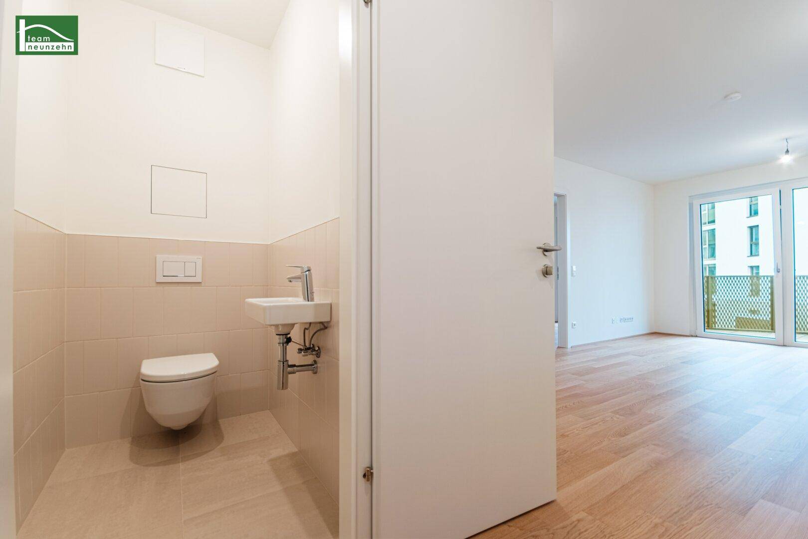 Modernes Gäste-WC mit wandhängender Toilette, kleinem Waschbecken und hellen Fliesen.