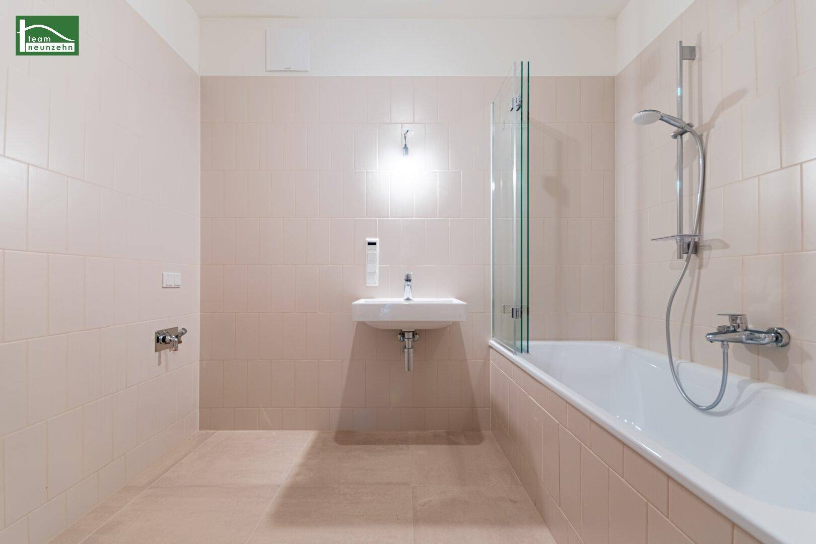 Modernes Badezimmer mit Badewanne, Duschabtrennung und hellen Fliesen.