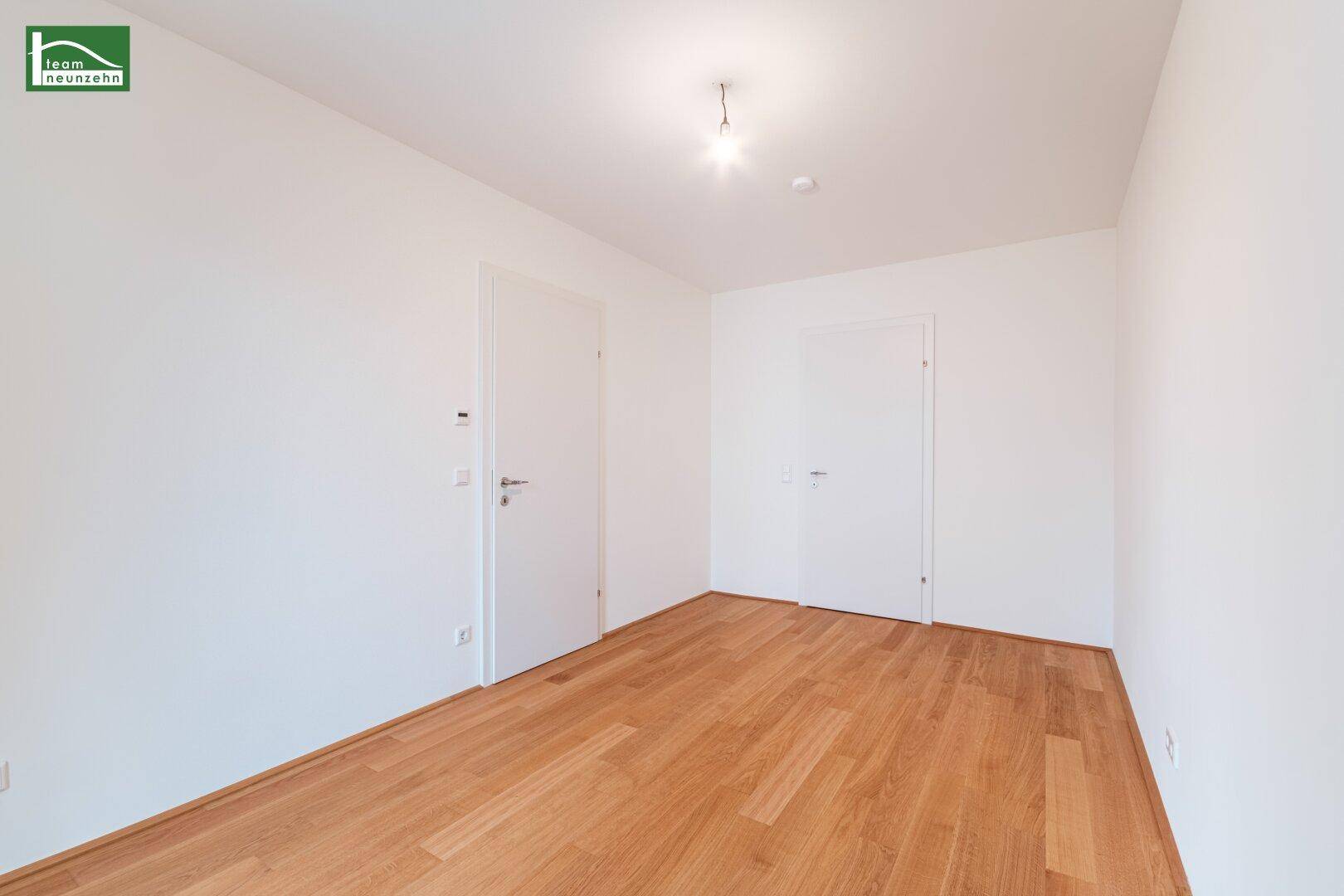 Unmöbliertes Zimmer mit Holzboden und zwei Türen, vielseitig nutzbar.