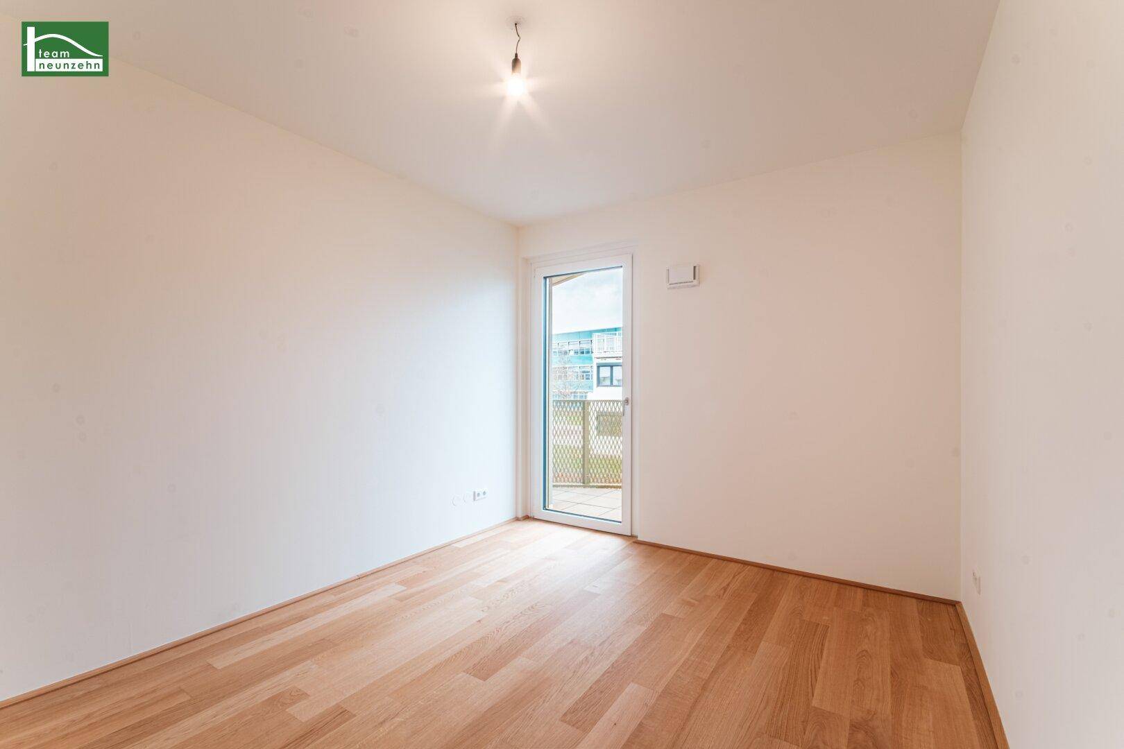 Helles, unmöbliertes Zimmer mit Holzboden und Balkonzugang, geeignet als Schlaf- oder Arbeitszimmer.