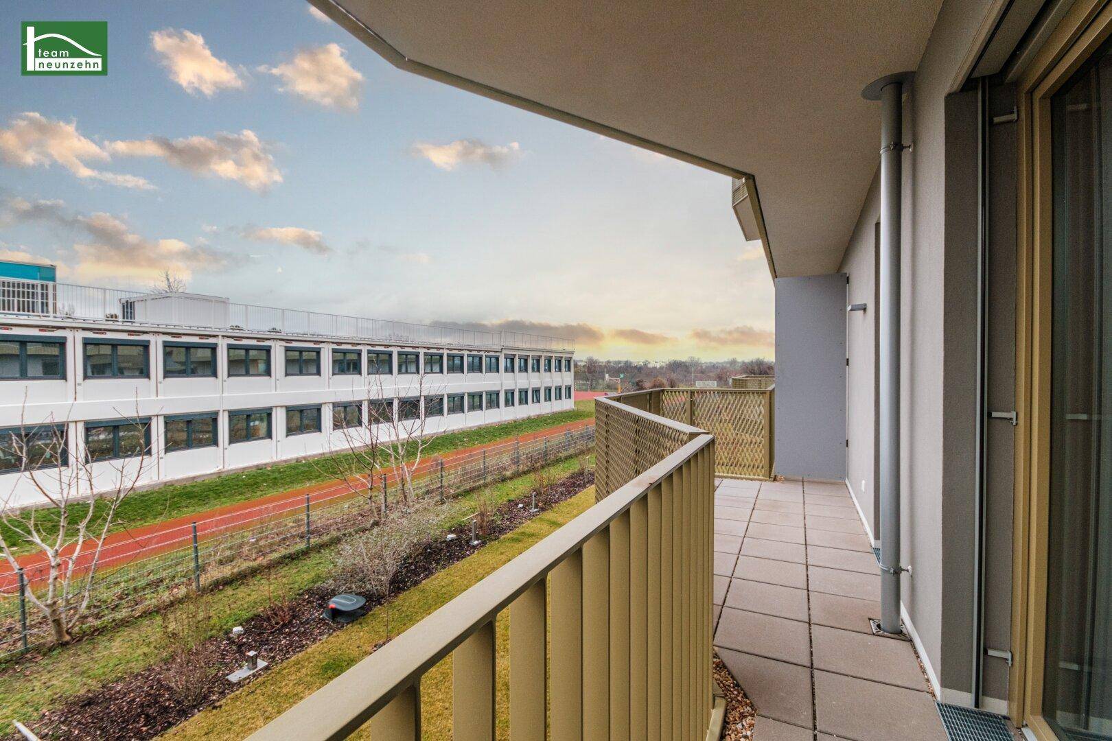 Geräumiger Balkon mit Blick auf eine Sportanlage und umliegende Gebäude, ideal zum Entspannen.