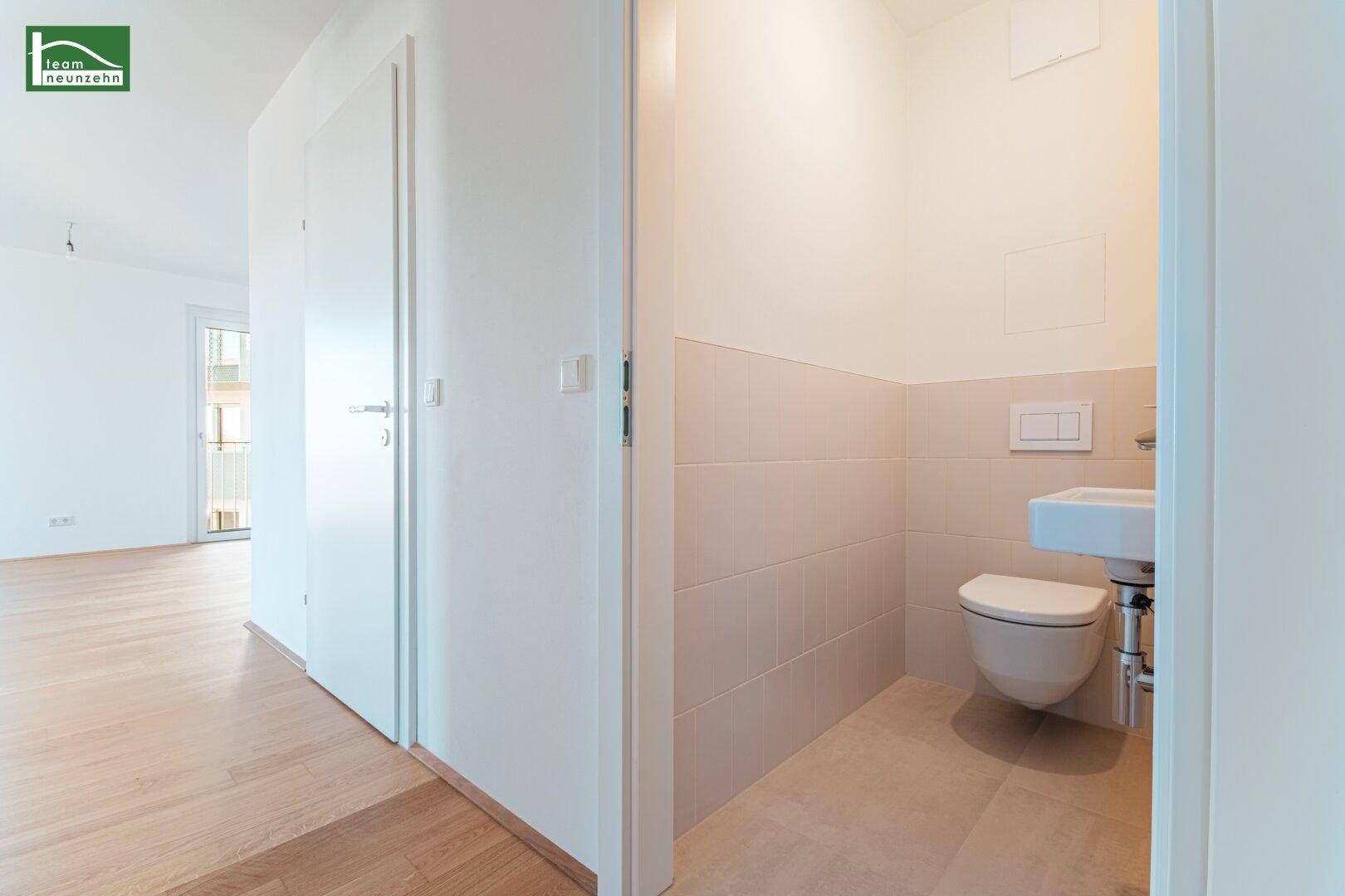 Separates Gäste-WC mit wandhängender Toilette und kleinem Waschbecken.