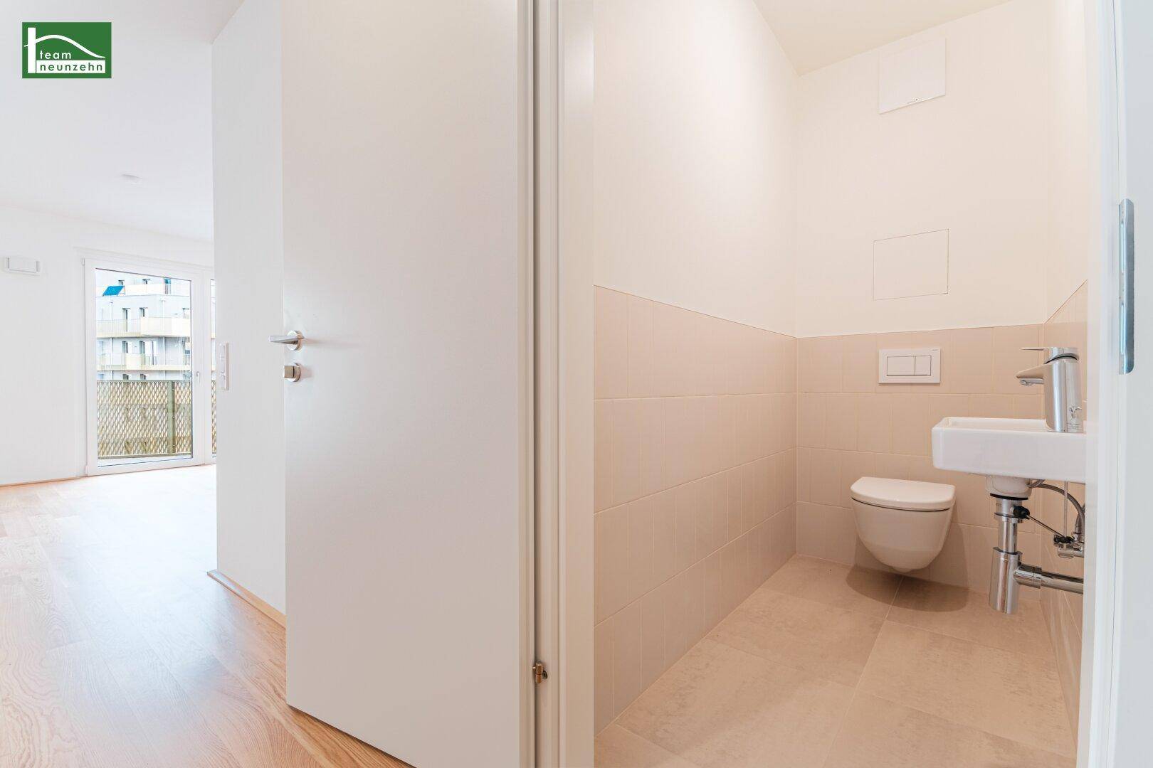 Modernes Gäste-WC mit Wand-WC und Waschbecken in hellen Fliesen, praktisch und funktional.