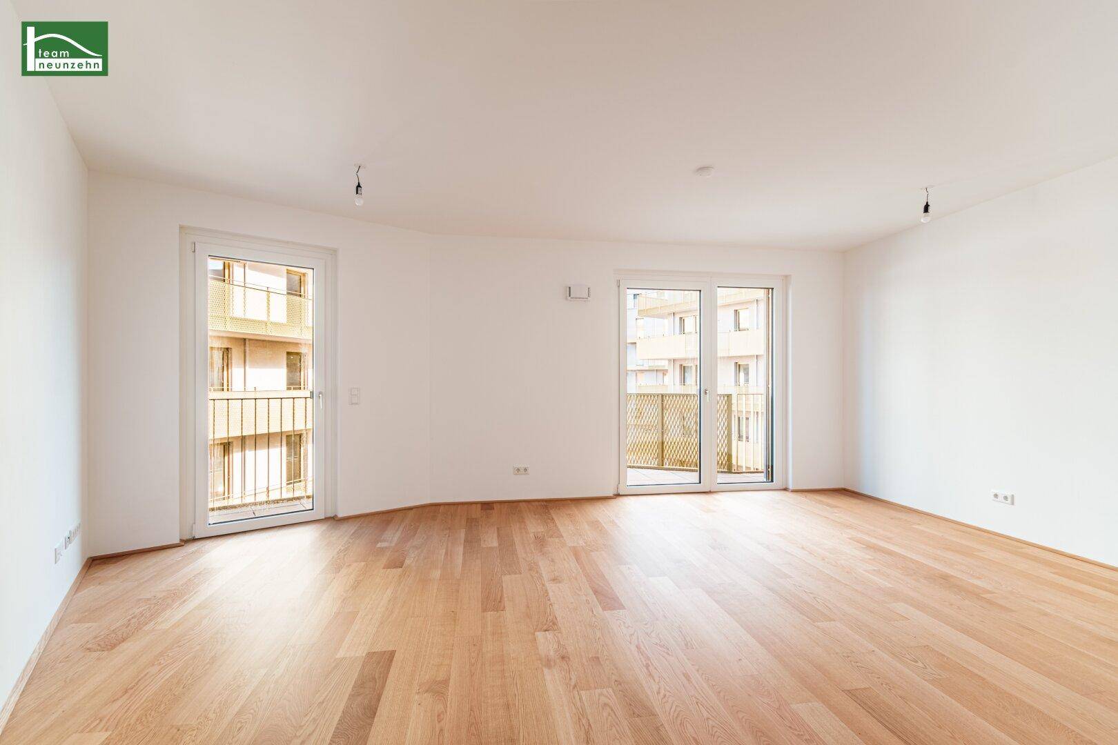 Helles Wohnzimmer mit Holzboden und Zugang zu einem französischen Balkon, bietet viel Tageslicht.