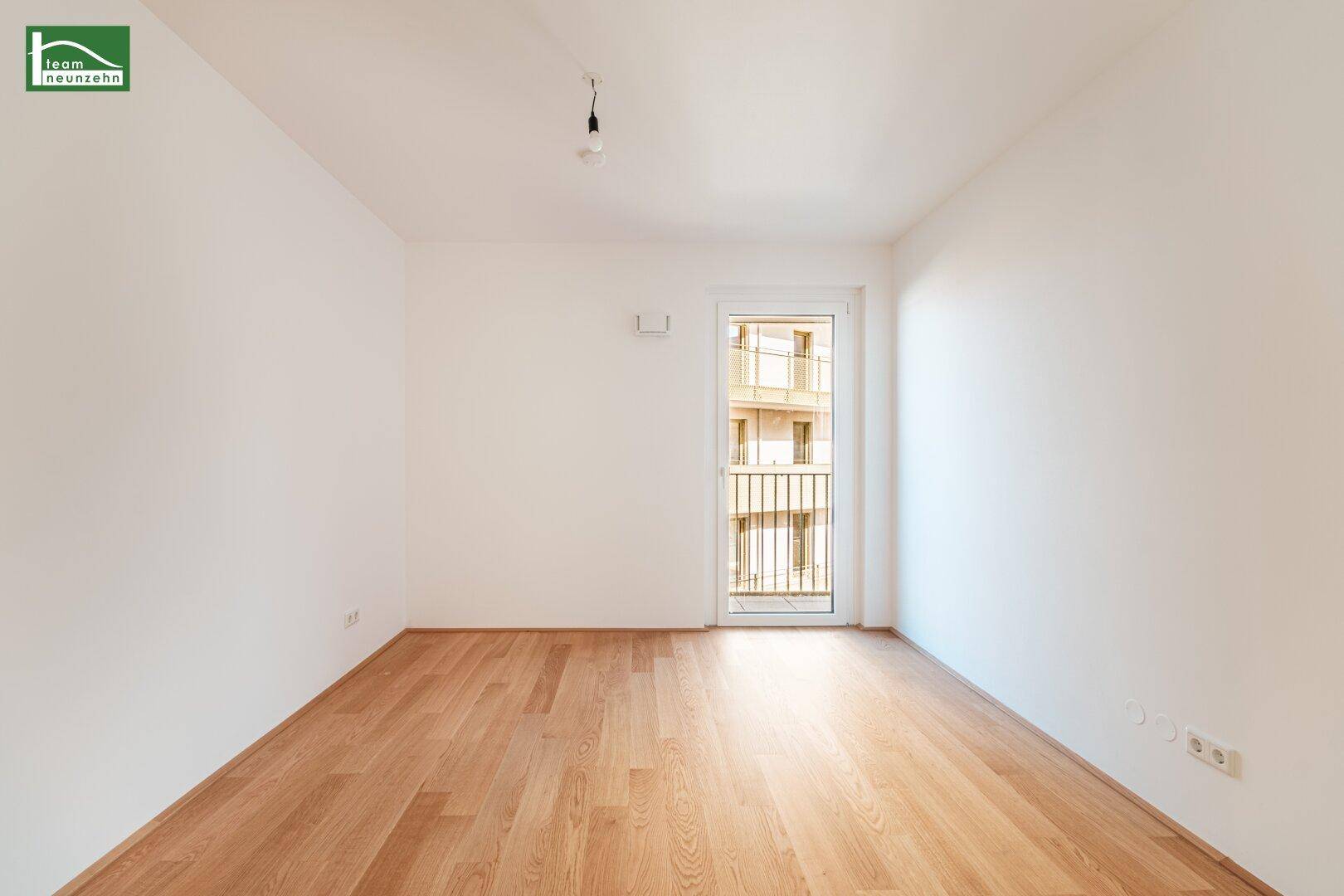 Leeres Schlafzimmer mit Holzboden und Zugang zu einem französischen Balkon, ideal für Ruhe.