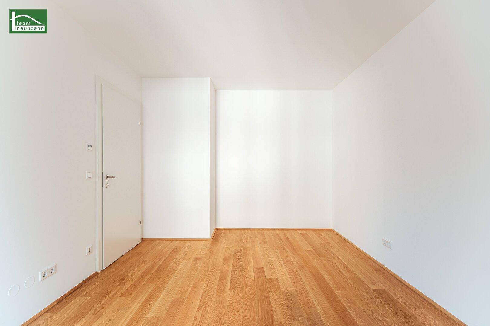 Leeres Schlafzimmer mit Holzboden und weiß gestrichenen Wänden, bereit für individuelle Gestaltung.