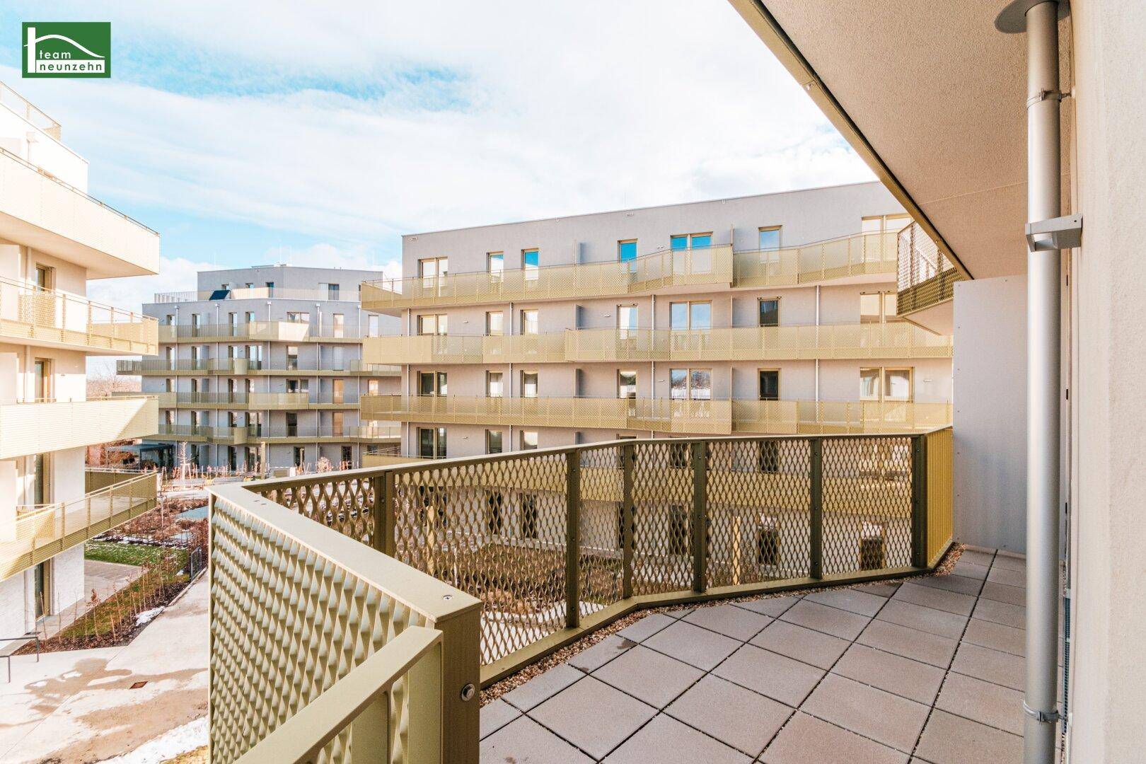 Großer Balkon mit moderner Metallbrüstung und weitem Blick über die Wohnanlage und Umgebung.