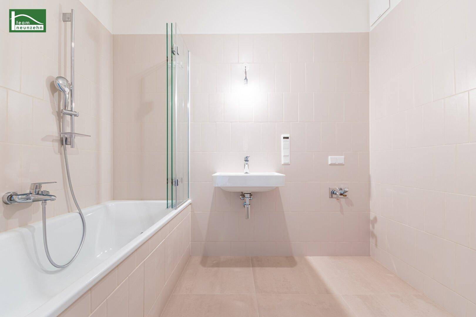 Modernes Badezimmer mit Badewanne, Duschabtrennung und kleinem Waschbecken.